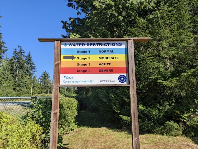 A sign showing water conservation regulations on the side of the Sunshine Coast Highway