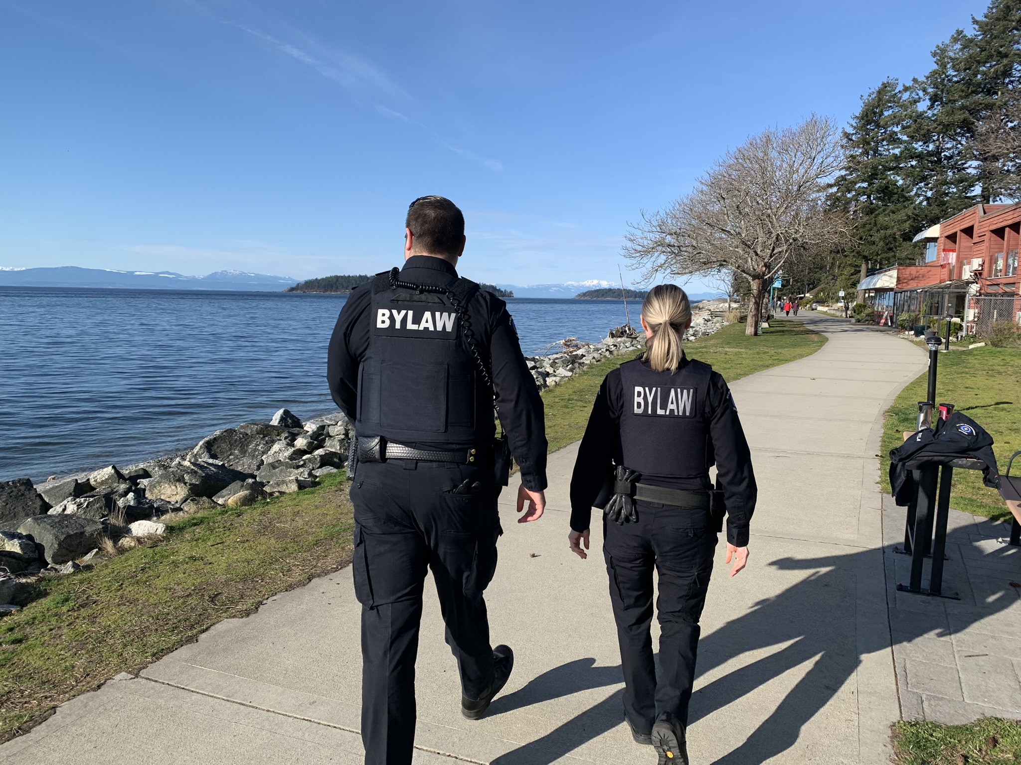 bylaw enforcement officers walk along the coast line