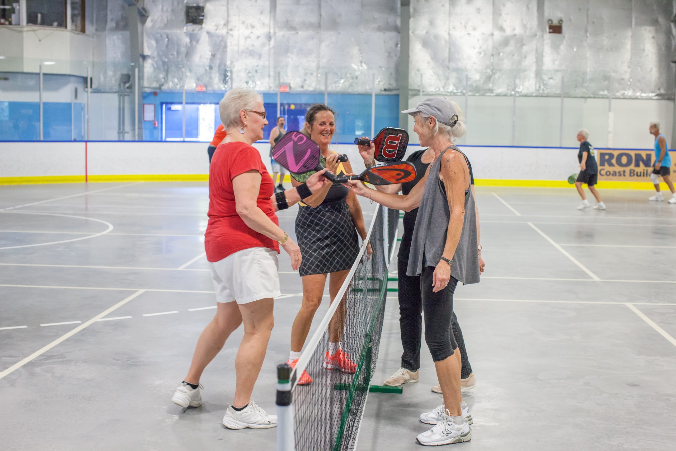four people meet at the net after plying pickleball
